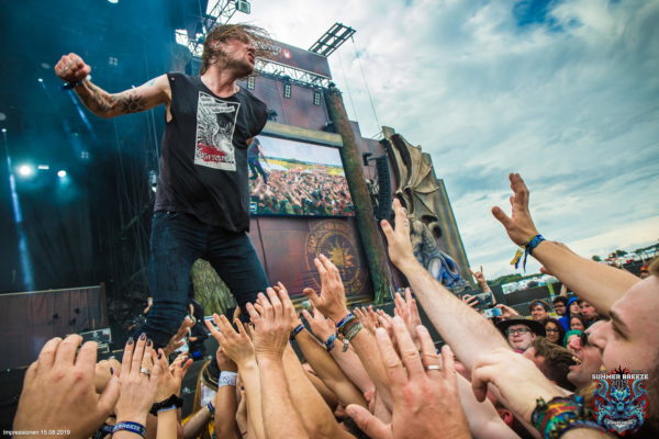 Festivalimpression vom Summer Breeze: Sänger der Band Kvelertak vor der Main Stage, Fans recken ihre Arme in den Himmel